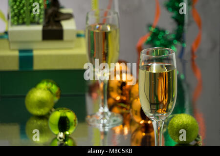 Deux verres de champagne et de paniers de Noël, cadeaux bouteille avec ruban de satin rouge, les pommes des cannes de bonbon, pommes de pin, branches d'ornements d'or guirlandes sur Banque D'Images