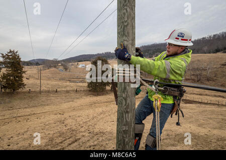 Brandon Joueur de contrat Sims a grimpé poteau au châssis pour les tenir sur le fil comme Virginia's BARC Electric Cooperative ouvre la voie dans la région de Lexington en Virginie, l'installation de câbles à fibres optiques le réseau électrique existant, ce qui permettra de porter à haute vitesse à large bande fiable pour le secteur pour la première fois. Les zones rurales où les entreprises et les consommateurs résidentiels utiliser le service à large bande sont plus susceptibles de profiter de l'augmentation des revenus, le taux de chômage plus faible et une plus forte croissance que celles qui n'ont pas le haut débit. Parce qu'à large bande offre la connectivité aux zones rurales, l'éducation, soins de santé et d'autres servic Banque D'Images