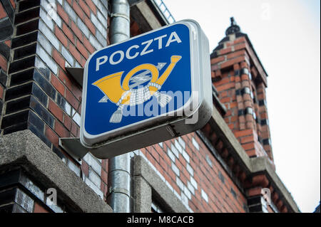 Cor du service postal (logo) sur le côté du bâtiment en briques rouges. Plaque de rue, de l'image jaune sur fond bleu dans la vieille ville historique de Torun, Pologne Banque D'Images