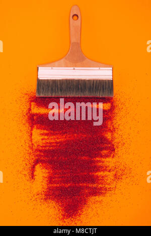 Vue supérieure de sable rouge pour la décoration et la brosse isolé sur orange Banque D'Images