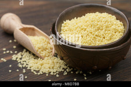 Couscous biologiques crus dans un bol sur la table. Selective focus Banque D'Images