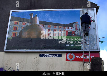 L'homme sur une échelle mise en place d'un nouveau panneau publicitaire Publicité, billboard de whisky jamesons une célèbre marque de whisky irlandais, l'Irlande de Skibbereen. Banque D'Images