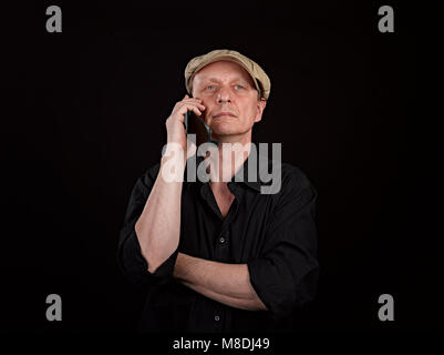Portrait d'une personne sérieuse avec son smartphone sur fond noir Banque D'Images