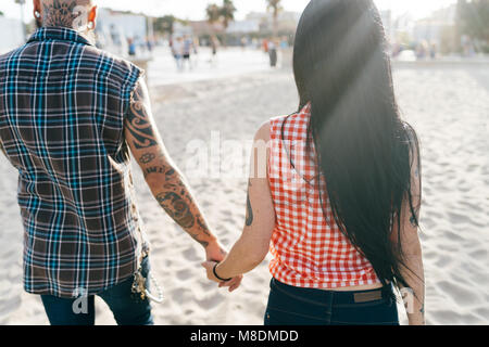 Hipster tatouée mature couple strolling on beach, vue arrière, Valencia, Espagne Banque D'Images