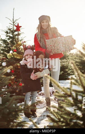 Mère et fille en forêt d'arbre de Noël avec des cadeaux de Noël, portrait Banque D'Images