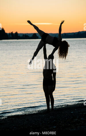 Couple practicing yoga on beach at sunset Banque D'Images