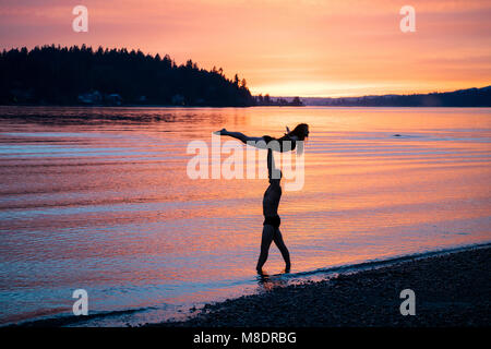 Couple practicing yoga on beach at sunset Banque D'Images