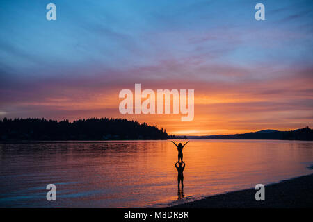 Couple practicing yoga on beach at sunset Banque D'Images