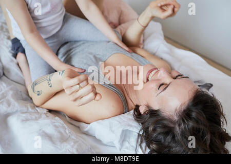 Mother and Daughter lying on bed, de jouer, rire, mid section Banque D'Images