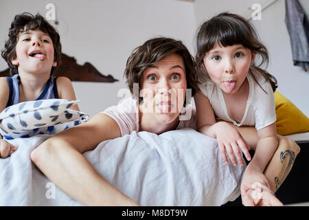 Portrait de mère, son fils et sa fille, allongé sur le lit, poussant l'out Banque D'Images