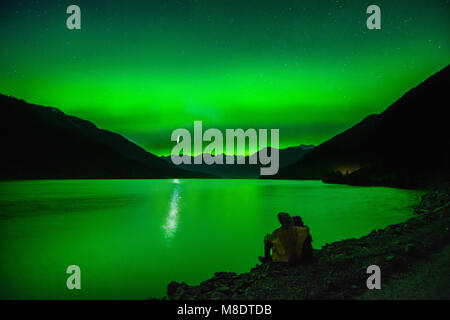 Couple assis à côté du lac Lillooet, regarder la northern lights, Pemberton, Colombie-Britannique, Canada Banque D'Images