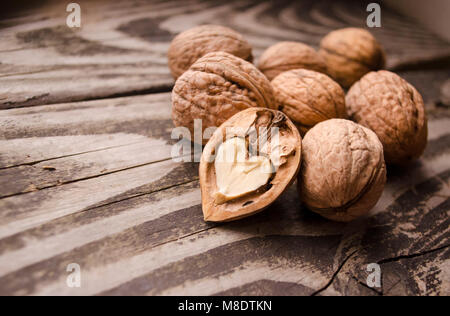 Les noix sur une table en bois texturé gris. Assortiment de noix isolé sur fond de bois ancien rustique et éclats de noyer avec base en forme de cœur. Banque D'Images