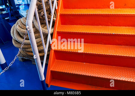 Escalier métallique orange vif à l'intérieur d'un ferry pour passagers avec un pont bleu Banque D'Images