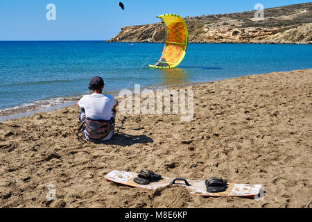 Kitesurfer avec parachute jaune et bord de mer se trouve sur la plage de sable paisible de l'océan contre le ciel clair le jour de l'été vue arrière Banque D'Images