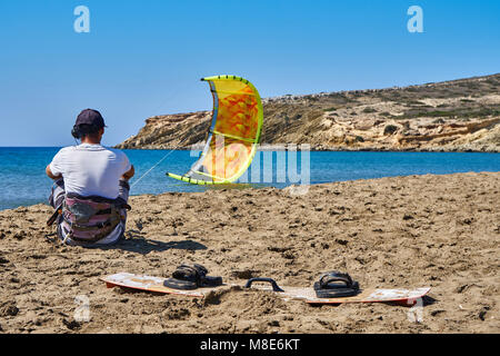 Kitesurfer avec parachute jaune et bord de mer se trouve sur la plage de sable paisible de l'océan contre le ciel clair le jour de l'été vue arrière Banque D'Images