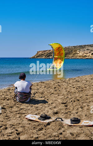 Kitesurfer avec parachute jaune et bord de mer se trouve sur la plage de sable paisible de l'océan contre le ciel clair le jour de l'été vue arrière Banque D'Images