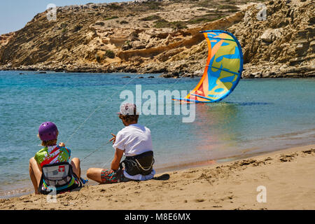 Des kitesurfers qualifiés avec parachute coloré s'assoient sur une plage de sable paisible sur l'océan, contre des falaises abruptes, le jour de l'été, vue arrière Banque D'Images