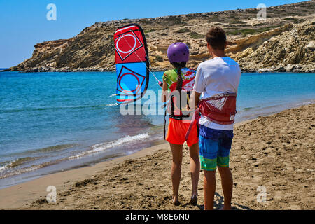 L'entraîneur enseigne à une jeune femme de faire du kitesurf sur une plage tranquille sur l'océan contre le ciel clair sur la vue arrière ensoleillée de jour d'été Banque D'Images