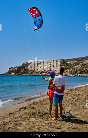 L'entraîneur enseigne à une jeune femme de faire du kitesurf sur une plage tranquille sur l'océan contre le ciel clair sur la vue arrière ensoleillée de jour d'été Banque D'Images