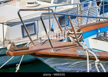 Bateau à moteur en bois amarré à la jetée avec des cordes sur l'eau de mer bleue reflétant la lumière du soleil vive le jour d'été vue de près Banque D'Images