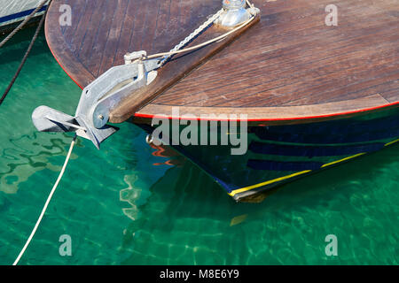 Bateau à moteur en bois amarré à la jetée avec des cordes sur l'eau de mer bleue reflétant la lumière du soleil vive le jour d'été vue de près Banque D'Images