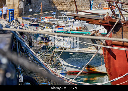 Différents bateaux amarrés à la jetée avec des cordes de couleur et des amers de rivage contre le bâtiment de brique orange sous la lumière du soleil d'été Banque D'Images