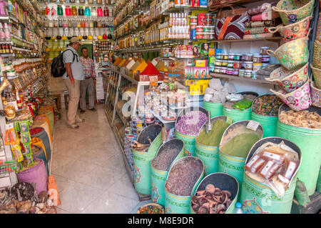 Le tourisme ou le client et le fournisseur de discuter les épices dans une petite boutique sur la place Jemaa el-Fna dans la médina de Marrakech, Maroc. Banque D'Images