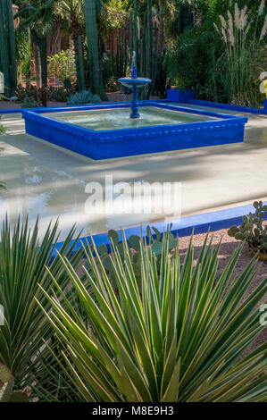 Le bleu de cobalt dotée d'une fontaine entourée de plantes dans le Jardin Majorelle, une attraction touristique à Marrakech, Maroc. Banque D'Images