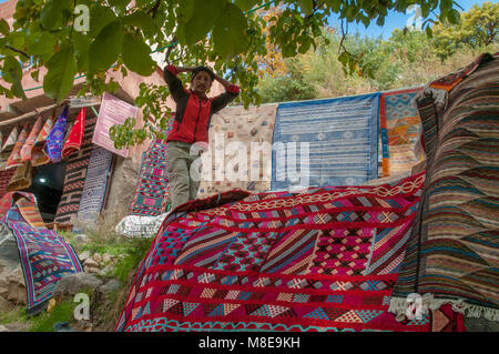 Guide de trekking marcher parmi les tapis à vendre en route vers les cascades de l'Ourika dans les montagnes de l'Atlas, au Maroc. Banque D'Images