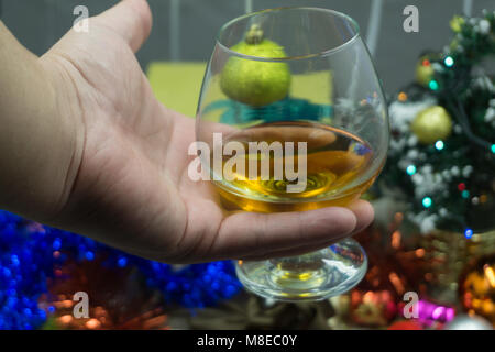 La main avec verre de cognac sur fond noir. Se concentrer sur la main avec le verre Banque D'Images
