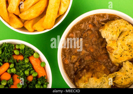 Goulasch de Bœuf britannique traditionnel, avec des boulettes sur un fond vert et un bol de frites et Légumes Banque D'Images
