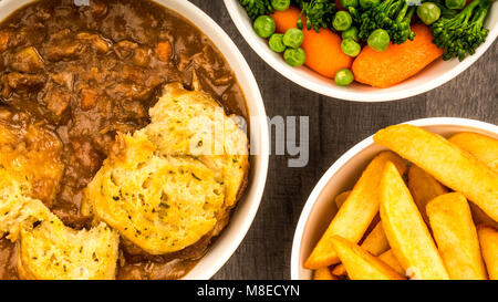 Goulasch de Bœuf britannique traditionnel, avec des boulettes et des jetons avec un mélange de légumes sur une table en bois foncé Banque D'Images