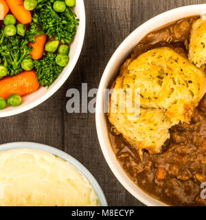 Goulasch de Bœuf britannique traditionnel, avec des boulettes et de la purée de pommes de terre et de légumes sur une table en bois foncé Banque D'Images