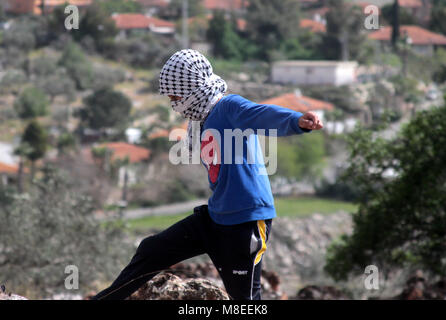 Les jeunes Palestiniens lancer des pierres au cours d'affrontements avec des soldats israéliens, à la suite d'une manifestation contre l'expropriation de terres palestiniennes par Israël dans le village de Kfar Qaddum. Mar 16, 2018. Les habitants de Kafr Qaddum ont tenir des manifestations hebdomadaires depuis 2011 contre des confiscations de terres pour l'expansion d'une colonie israélienne locale, ainsi que la fermeture de la route du sud du village à Naplouse par les forces israéliennes depuis 2003. L Kafr Qaddum village est situé dans le nord de la Cisjordanie, district de Qalqiliya Crédit : Mohammed Turabi/ImagesLive/ZUMA/Alamy Fil Live News Banque D'Images