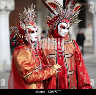 Venise, Italie - 5 Février, 2018 : la femme et l'homme avec une superbe robe rouge et or près de Le Palais Ducal durant la carnaval vénitien Banque D'Images