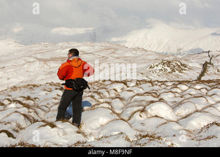 Un marcheur sur Wansfell regardant vers la Kentmere fells en hiver la neige, Lake District, UK. Banque D'Images