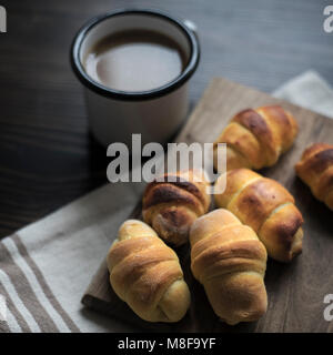 Mini croissants remplis avec du fromage et du café sur fond de bois Banque D'Images