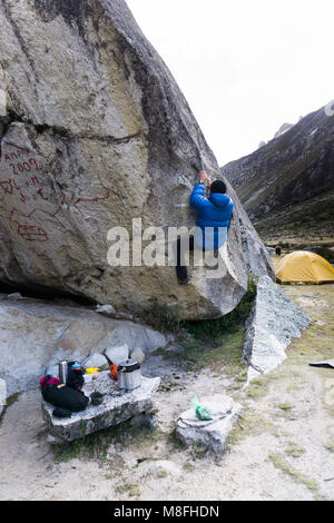 Homme d'alpiniste dans un blue Down Jacket de tenter un grand rocher à un camp de base dans la Cordillère Blanche au Pérou Banque D'Images