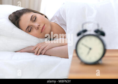 Belle jeune femme et heureuse alors que dormir confortablement au lit et souriant béatement Banque D'Images