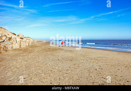 Deux dames de marcher un chien sur la plage de Norfolk est Winterton-sur-Mer, Norfolk, Angleterre, Royaume-Uni, Europe. Banque D'Images