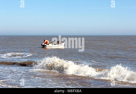 Un petit bateau de pêche côtière avec deux hommes à bord de mettre à la mer sur la côte de Norfolk à Winterton-sur-Mer, Norfolk, Angleterre, Royaume-Uni, Europe. Banque D'Images