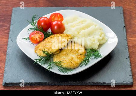 Une viande juteuse deux les galettes sur une plaque blanche avec des tomates cerises et de la purée de pommes de terre. Banque D'Images