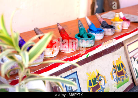 Un affichage de mortier en pierre blanche des pilons avec différentes couleurs de poudre au marché de l'horloge à Jodhpur en Inde. Ils sont placés sur un bord peint en rouge. Banque D'Images