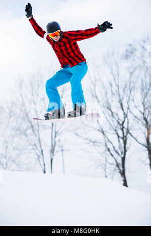 Photo de l'homme sportif avec saut de planche à neige en resort Banque D'Images