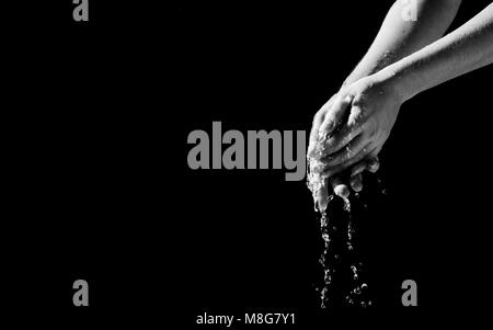 Woman's hands avec de l'eau splash sur fond noir. Banque D'Images