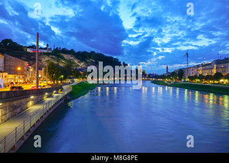 Salzbourg, Autriche - Le 6 septembre 2017 ; Vue de nuit le long de la rivière Salzach en longue exposition dark ciel nuageux et le builsdings relecting feux sur les calmes Banque D'Images