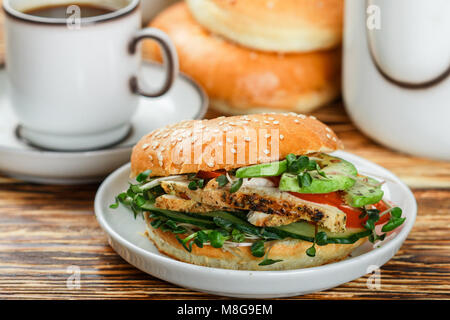 Graines de sésame poulet bagels de grains entiers avec grill, Microgreens, concombre et avocat sur plaque blanche sur fond gris. Petit-déjeuner sain concept . S Banque D'Images