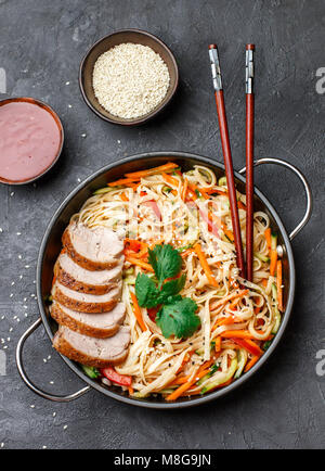 Les nouilles Udon avec des légumes (carottes, poivrons, courgettes, concombre, l'oignon, la coriandre, l'ail), les canards et les graines de sésame. La faire revenir. Selective focus Banque D'Images