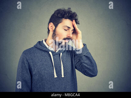 Young casual hipster avec barbe souffrant de malheur à la fatigue tout en se frottant la tête. Banque D'Images