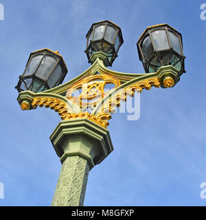 Le Londres victorien ornate grappe de trois lampes de la rue lanterne octogonale sur la chaussée à côté de la colonne de fer de fonte de Westminster Bridge London England UK Banque D'Images